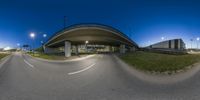 an overpass crossing over a highway at night, near green grass and light poles