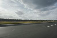 a speed limiter sitting on a highway with the sky and trees behind it in the distance