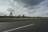 a speed limiter sitting on a highway with the sky and trees behind it in the distance