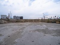 a empty parking lot in front of construction cranes and large buildings at dusk in an industrial area