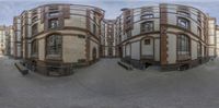 two buildings are seen through the same fisheye lens in this image, there is a bench to go on the sidewalk