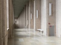 a bunch of benches in a corridor with stone walls and gray floors and grey columns