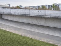 a wall of concrete near the side of a road with a sign on it next to an empty lot