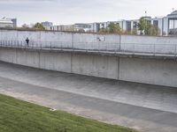 a wall of concrete near the side of a road with a sign on it next to an empty lot