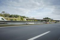 the side of a highway with cars going down it with cloudy blue sky above it