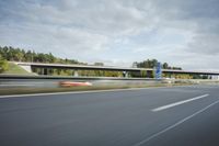 the side of a highway with cars going down it with cloudy blue sky above it