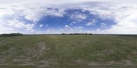 a field that is very close to the ground with clouds in the background and some grass