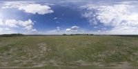 a field that is very close to the ground with clouds in the background and some grass