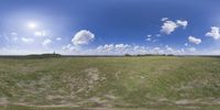 a field that is very close to the ground with clouds in the background and some grass