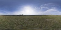 a field that is very close to the ground with clouds in the background and some grass