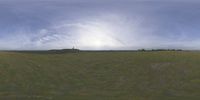 a field that is very close to the ground with clouds in the background and some grass