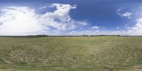 a field that is very close to the ground with clouds in the background and some grass