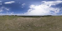 a field that is very close to the ground with clouds in the background and some grass