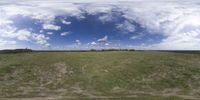 a field that is very close to the ground with clouds in the background and some grass