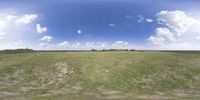 a field that is very close to the ground with clouds in the background and some grass