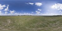 a field that is very close to the ground with clouds in the background and some grass