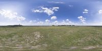 a field that is very close to the ground with clouds in the background and some grass