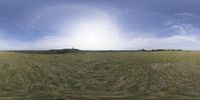 a field that is very close to the ground with clouds in the background and some grass