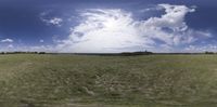 panorama photo taken by an apple camera on the road with grass on either side and a grassy hill on the other side