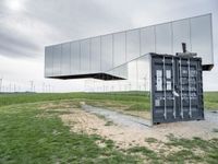 a reflection of wind turbines is in a glass wall on a grassy field by grass