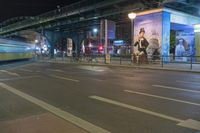 the bus is traveling in the city along the road at night time with billboards on its side