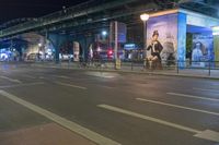 the bus is traveling in the city along the road at night time with billboards on its side