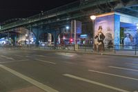 the bus is traveling in the city along the road at night time with billboards on its side