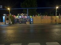 a street at night with no traffic on it's side and signs in front