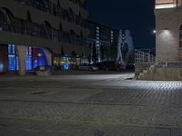 a person walking down the sidewalk in front of a building at night with an umbrella