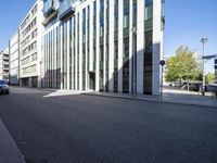 a building with glass walls along a city street side walk from the corner to the sidewalk