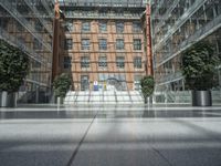 an open atrium is shown in this image, with a modern building behind it and plants growing between the floors