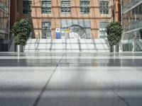 an open atrium is shown in this image, with a modern building behind it and plants growing between the floors