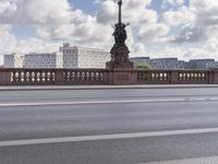 the man rides his bicycle down the bridge in front of a street light and traffic on a sunny day