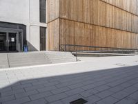 a building that is standing in the sun outside of it, with some stairs and steps