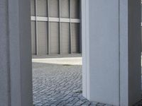 a young boy in sunglasses walks near the columns outside a building in a parking lot