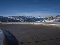 a lone skateboarder rides along an empty snow covered road with mountains in the background