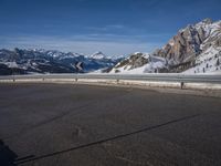 a lone skateboarder rides along an empty snow covered road with mountains in the background