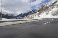 a long road with a snowy slope and mountains in the background as seen from a speeding vehicle