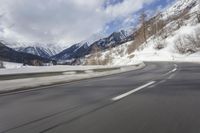 a long road with a snowy slope and mountains in the background as seen from a speeding vehicle