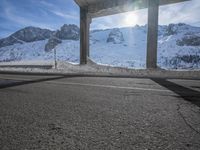 an empty parking lot next to mountains in the wintertime with a roof over and sky overhead