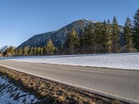 a person is riding his bike down a road with snow on the ground and trees