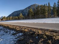 a person is riding his bike down a road with snow on the ground and trees