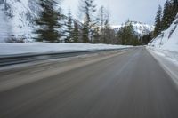 a blurred shot of trees and a mountain road in winter time, with blurry motion