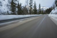 a blurred shot of trees and a mountain road in winter time, with blurry motion