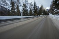 a blurred shot of trees and a mountain road in winter time, with blurry motion