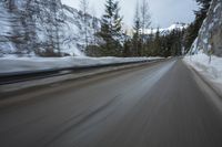 a blurred shot of trees and a mountain road in winter time, with blurry motion