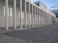 a walkway in front of a large white building with white pillars and columns that lead through it