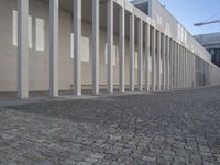 a walkway in front of a large white building with white pillars and columns that lead through it