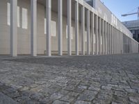 a walkway in front of a large white building with white pillars and columns that lead through it