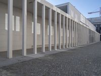 a walkway in front of a large white building with white pillars and columns that lead through it